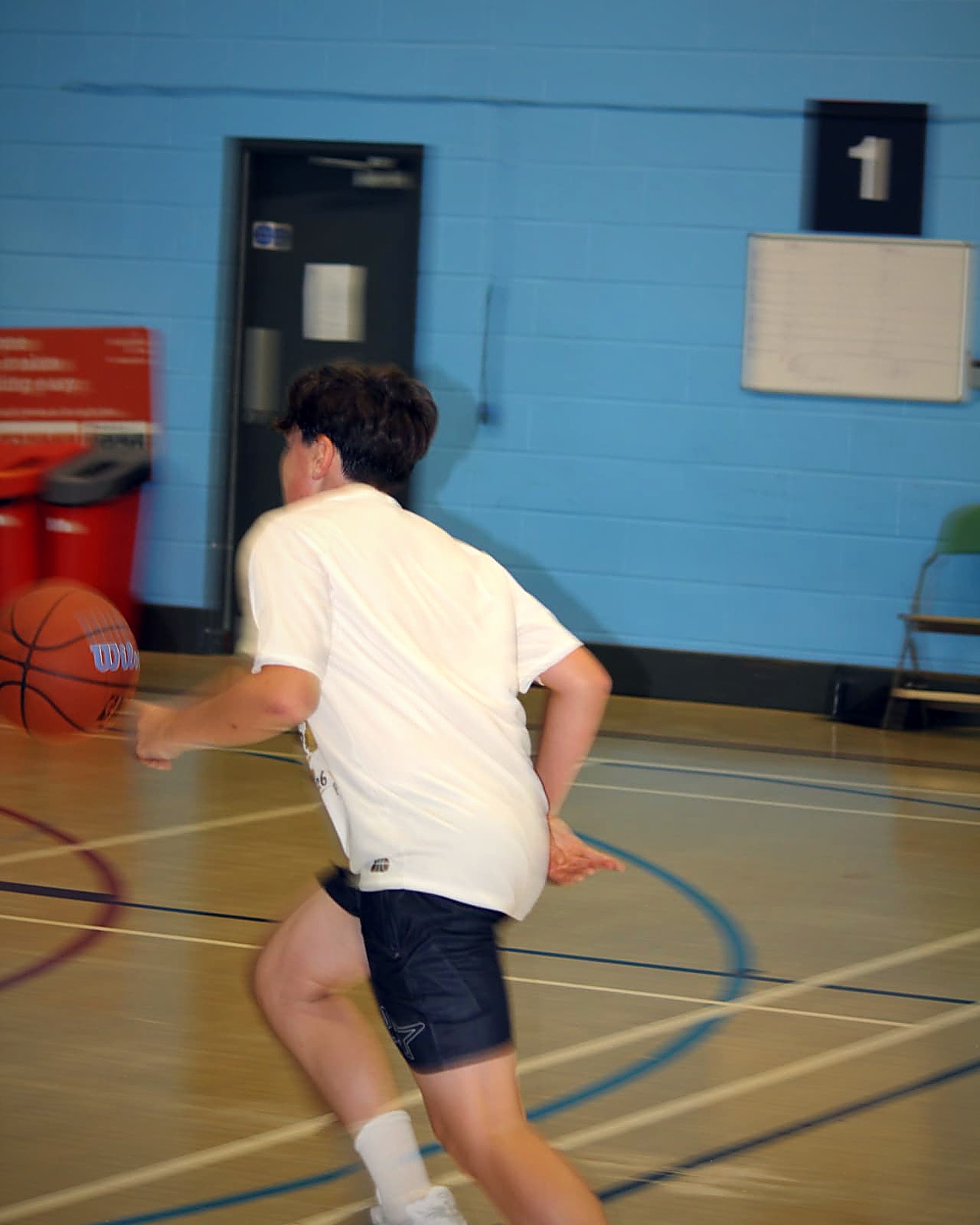A young player sprinting up court in a PHB basketball session