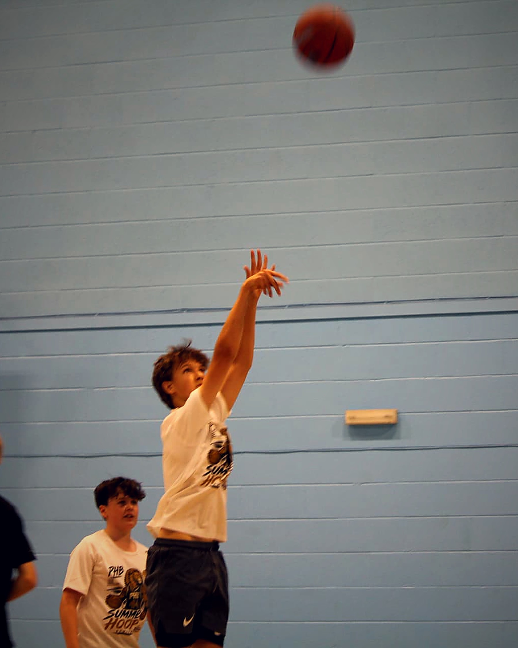 A young participant following through on a jump shot during a PHB basketball session