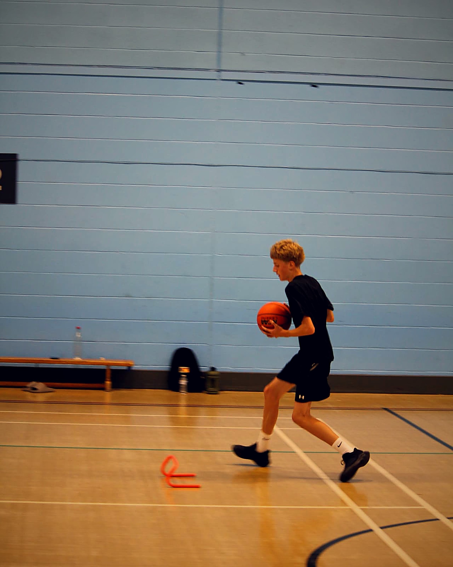 A participant running a court drill with hurdles during a PHB session
